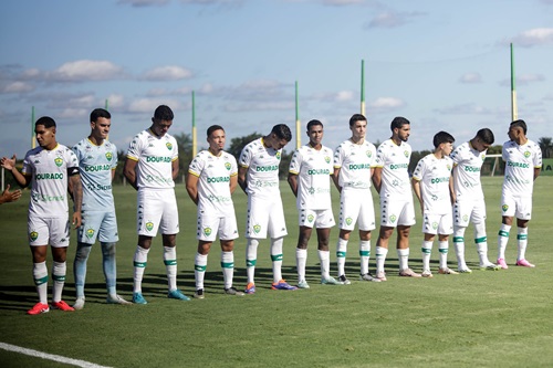 Elenco do Sub-20 do Cuiabá perfilado no gramado antes do início da partida, todos com uniforme branco e postura de concentração.