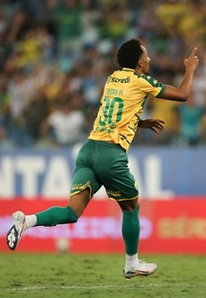 Lucas Mineiro., celebra um gol correndo em direção à torcida, apontando para o alto com o dedo indicador.