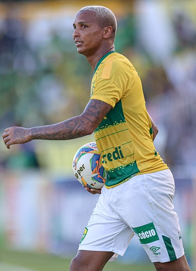 atacante Deyverson caminhando em campo com a bola na mao, com a camisa amarela e calção branco do cuiaba ec.