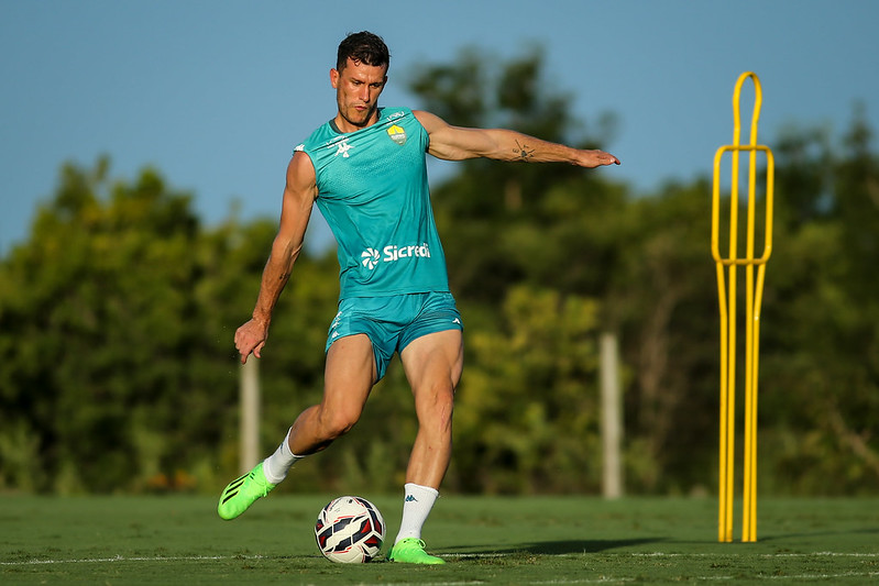 Nathan Cardoso em ação, chutando a bola em treino, vestindo o uniforme verde-água sem mangas.