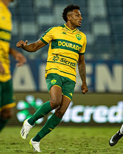 Guilherme Mariano em ação durante partida pelo Cuiabá, vestindo o uniforme amarelo e verde do time, em movimento no campo de jogo.