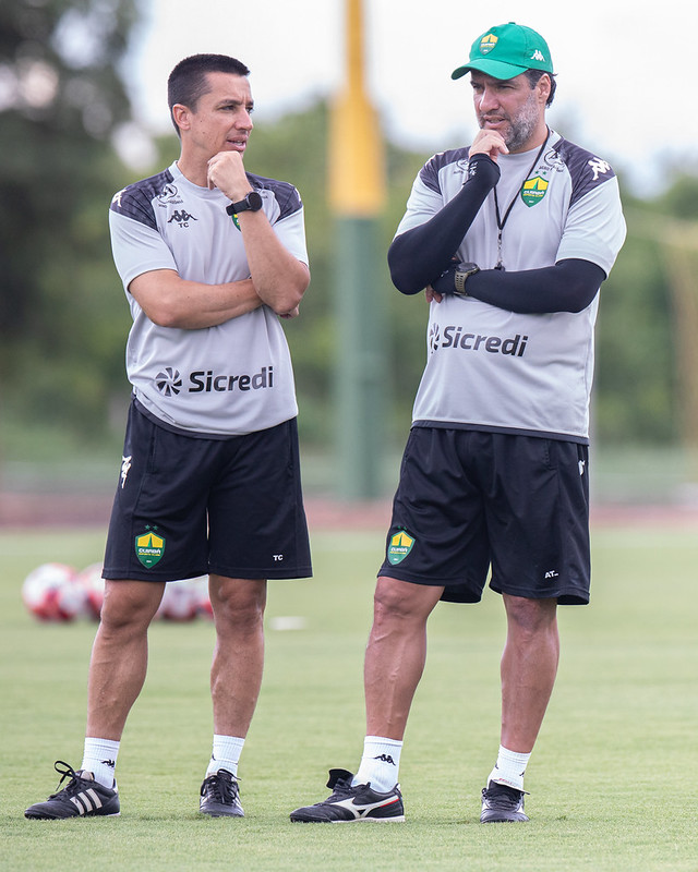 Técnico Eduardo Barros e membro da comissão técnica do Cuiabá conversam à beira do campo durante treinamento de preparação para o Campeonato Mato-grossense 2026.