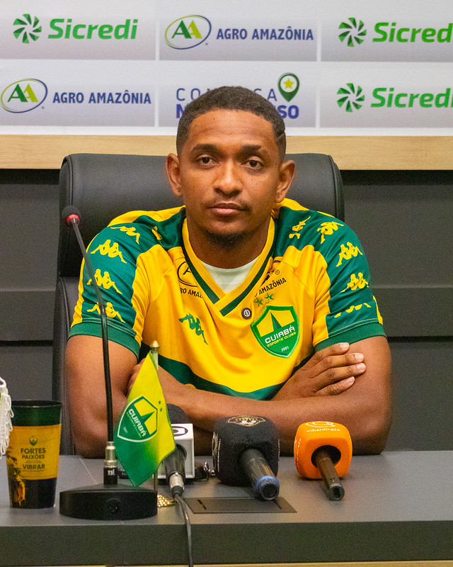 Atacante Hernandes durante coletiva de apresentação no Cuiabá Esporte Clube, vestindo a camisa auriverde na sala de imprensa.