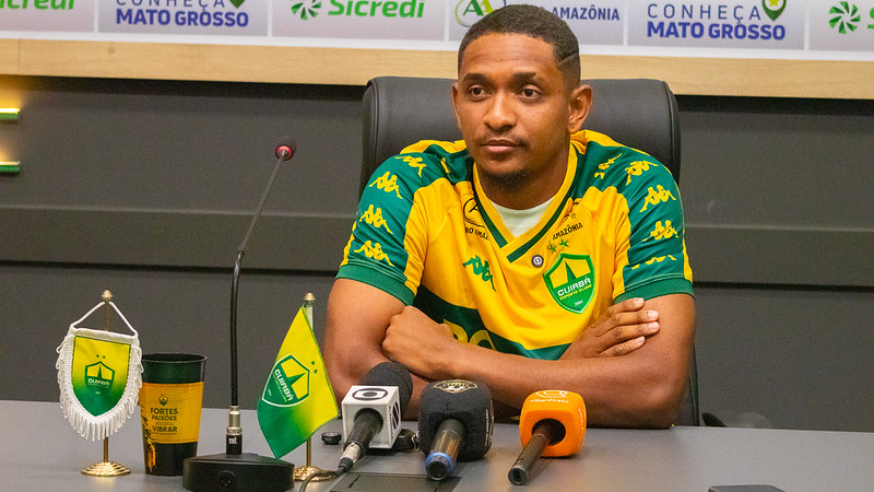 Atacante Hernandes durante coletiva de apresentação no Cuiabá Esporte Clube, vestindo a camisa auriverde na sala de imprensa.
