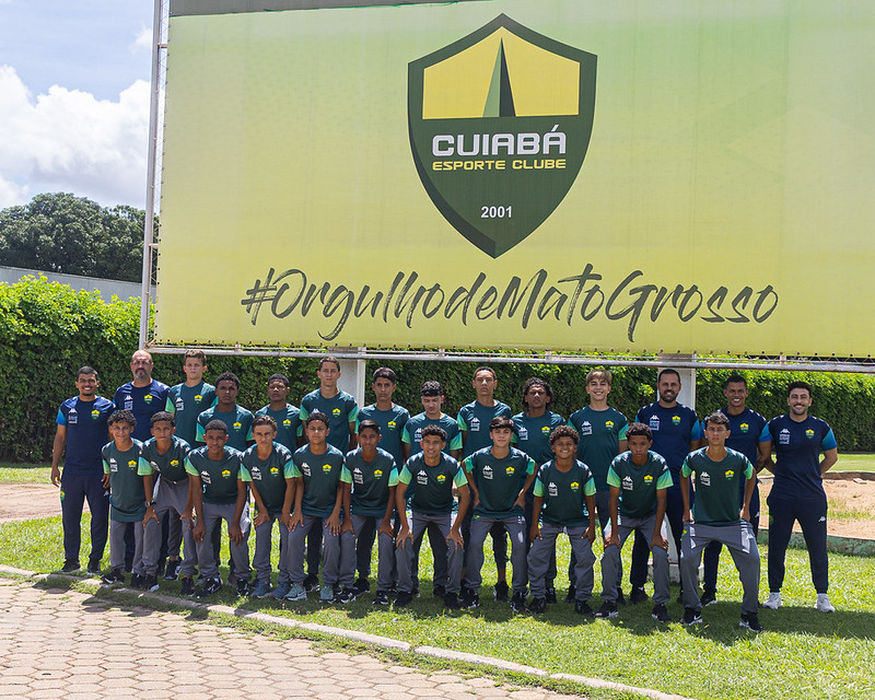 Elenco Sub-14 do Cuiabá Esporte Clube posando para foto oficial antes da disputa da Sfera Cup, em frente ao painel com o escudo do clube e a frase “Orgulho de Mato Grosso”