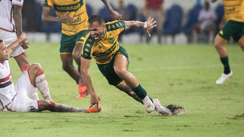 Jogador do Cuiabá disputa bola sob chuva intensa durante jogo contra o Botafogo-SP na Arena Pantanal pela Série B