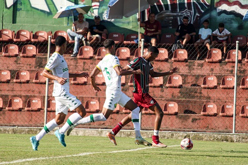 Jogador do Fluminense Sub-20 conduz a bola enquanto é marcado por dois jogadores do Cuiabá durante partida do Brasileirão Sub-20 no Estádio Marcelo Vieira.