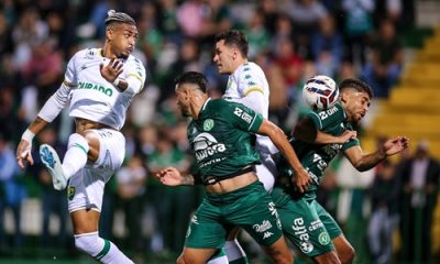 Derik Lacerda, atacante do Cuiabá, salta para finalizar a jogada em meio à marcação da Chapecoense, em partida pela Série B na Arena Condá.