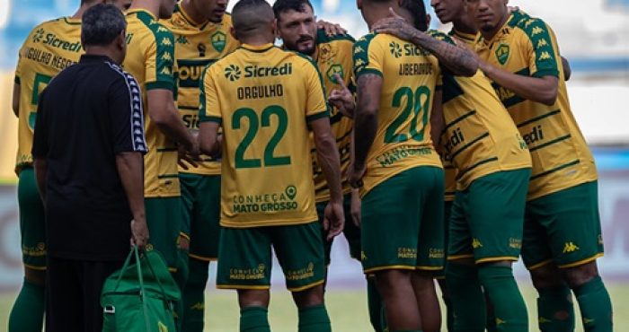 O time do Cuiabá reunido no centro do campo, possivelmente em uma roda de conversa antes ou durante o jogo.