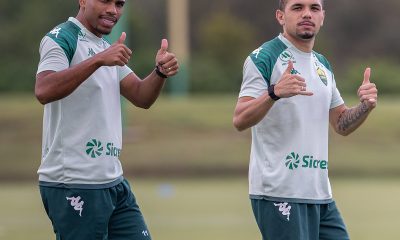 Dois jogadores do Cuiabá Esporte Clube durante treino no CT, vestindo uniforme branco e verde, fazendo sinal positivo com as mãos antes da estreia no Campeonato Mato-grossense.