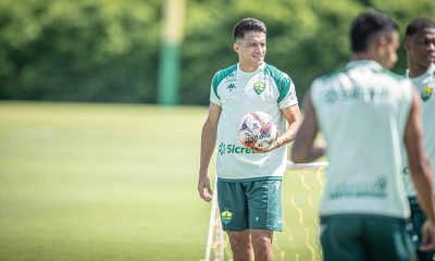 O Yamil do Cuiabá está em pé no centro do campo, segurando uma bola, durante uma pausa ou instrução no treino.