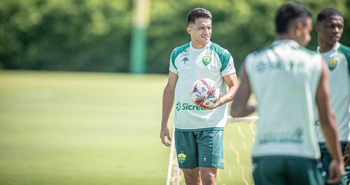 O Yamil do Cuiabá está em pé no centro do campo, segurando uma bola, durante uma pausa ou instrução no treino.