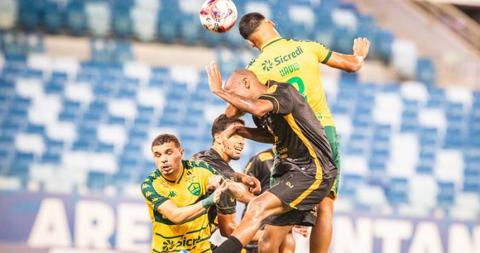 Jogadores de Cuiabá e Sport Sinop disputam bola pelo alto durante partida do Campeonato Mato-Grossense na Arena Pantanal.