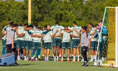 Retrata o elenco completo em um momento de união no gramado, formando um círculo antes ou depois de uma sessão de treino.