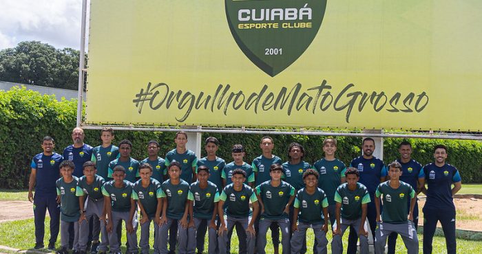 Elenco Sub-14 do Cuiabá Esporte Clube posando para foto oficial antes da disputa da Sfera Cup, em frente ao painel com o escudo do clube e a frase “Orgulho de Mato Grosso”