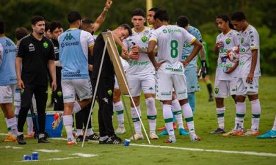 Jogadores do Cuiabá reunidos em treino no campo, com comissão técnica orientando taticamente a equipe.