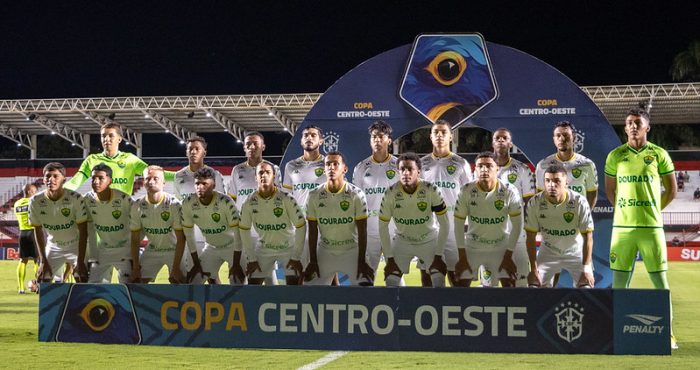 Uma foto clássica da escalação, mostrando os onze titulares e os goleiros. Os goleiros vestem uniformes amarelo-neon/verde de alta visibilidade, enquanto os jogadores de linha usam o tradicional uniforme branco de mandante/visitante com detalhes em verde.