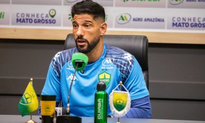 Marcelo Carné durante entrevista coletiva do Cuiabá Esporte Clube, falando ao microfone em sala de imprensa, com backdrop de patrocinadores ao fundo.