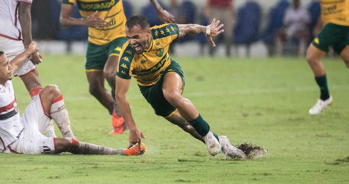 Jogador do Cuiabá disputa bola sob chuva intensa durante jogo contra o Botafogo-SP na Arena Pantanal pela Série B