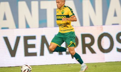 Jogador do Cuiabá EC conduz a bola durante partida na Arena Pantanal, vestindo uniforme amarelo e verde do Dourado em lance ofensivo contra o Novorizontino pela Série B.