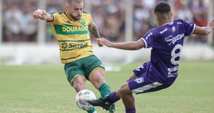 “Atacante André do Cuiabá em ação durante o primeiro jogo da semifinal contra o Primavera, disputando a bola com o adversário.”