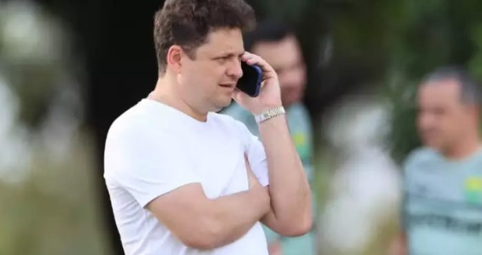 Presidente do Cuiabá aparece falando ao telefone à beira do campo, com expressão séria durante momento de tensão após partida.