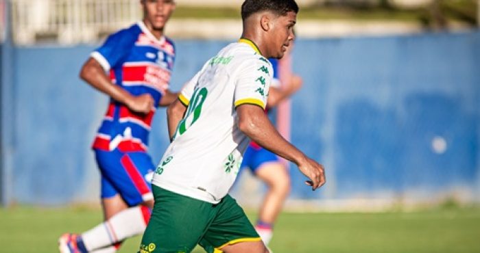 Jogador do Cuiabá Sub-20 conduz a bola durante partida contra o Fortaleza, usando uniforme branco e verde, com adversário ao fundo vestindo o uniforme tricolor do time cearense, em jogo válido pelo Campeonato Brasileiro Sub-20.
