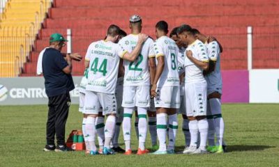 "Foto do time reunido no meio de campo para a última reunião antes da partida, com os jogadores ouvindo atentamente a orientação do capitão."