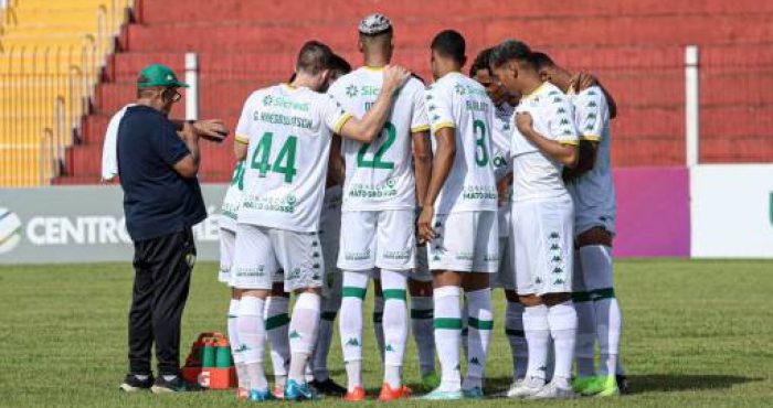 "Foto do time reunido no meio de campo para a última reunião antes da partida, com os jogadores ouvindo atentamente a orientação do capitão."