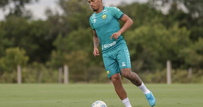 "Jogador Denilson durante treino do Cuiabá, focado na preparação para a semifinal do Campeonato Mato-Grossense. Ele aparece em ação no campo, demonstrando concentração e dedicação."