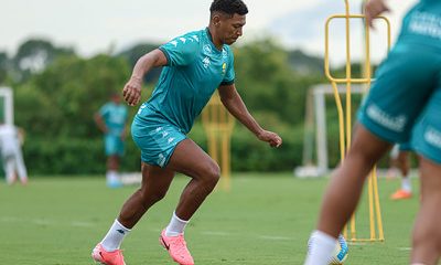 "Emerson Negueba durante treino com uniforme de treino verde do Cuiabá, realizando exercício de agilidade no gramado."