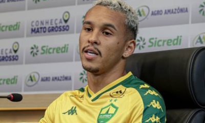 Entrevista com Juan Christyan, jogador do Cuiabá EC, falando sobre a preparação do time. Ele veste o uniforme oficial do clube e responde às perguntas dos jornalistas em uma coletiva de imprensa.