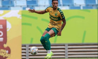 "Lucas Cardoso, atacante do Cuiabá EC, em ação durante uma partida de futebol, driblando um defensor adversário."