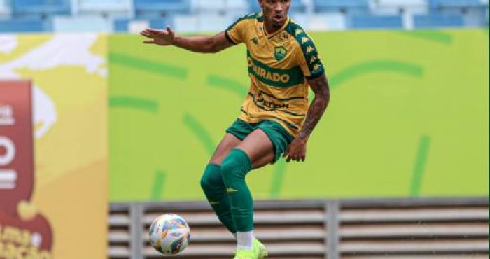 "Lucas Cardoso, atacante do Cuiabá EC, em ação durante uma partida de futebol, driblando um defensor adversário."