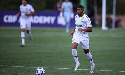 Jogador do Cuiabá Sub-20 conduz a bola durante partida do Campeonato Brasileiro Sub-20, vestindo uniforme branco com detalhes verdes e a braçadeira de capitão.