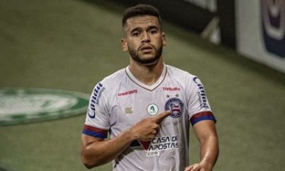 Patrick de Lucca aponta para o escudo do Bahia durante partida, demonstrando entrega e identificação com o clube.