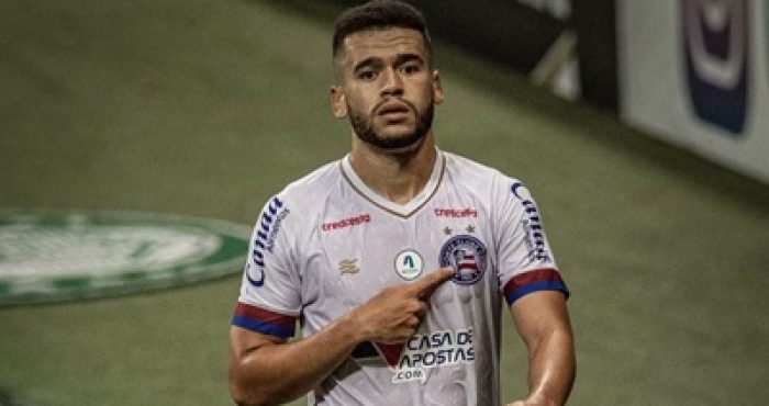 Patrick de Lucca aponta para o escudo do Bahia durante partida, demonstrando entrega e identificação com o clube.