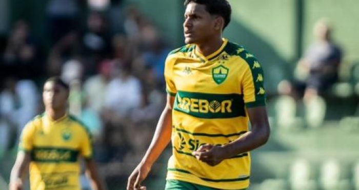 "Widney, atacante do Cuiabá Sub-17, em ação durante partida. O jovem jogador veste o uniforme verde e amarelo do Dourado, demonstrando concentração e habilidade em campo."