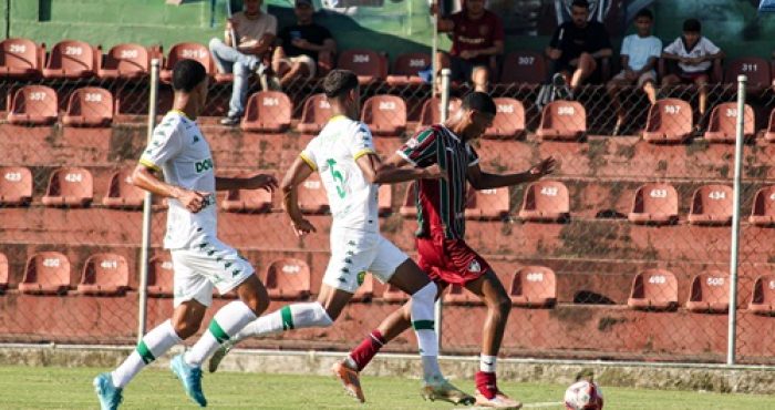 Jogador do Fluminense Sub-20 conduz a bola enquanto é marcado por dois jogadores do Cuiabá durante partida do Brasileirão Sub-20 no Estádio Marcelo Vieira.
